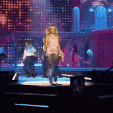 a woman in a pink dress is walking on stage