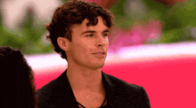 a young man with curly hair is wearing a black jacket