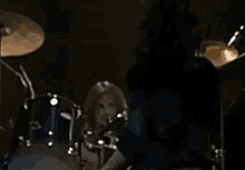 a woman is playing a drum set in a dark room .