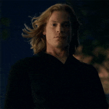 a man with long blonde hair wearing a black jacket
