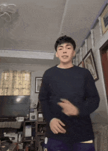 a man in a black sweater is dancing in front of a television