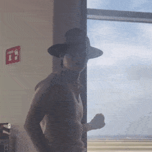 a man wearing a hat is standing in front of a window with a red sign that says exit