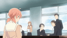 a girl with pink hair stands in a classroom with other students