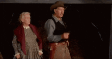 a man in a top hat is standing next to a woman laying in a bed .
