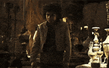 a man with curly hair is standing in a dark room holding a gun .
