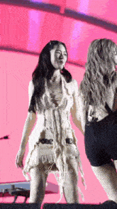 a woman in a white dress is standing next to another woman in black shorts