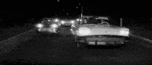a black and white photo of two cars driving down a highway