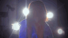 a woman with long red hair is standing in front of a row of lights .
