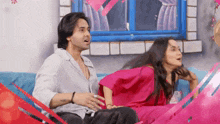a man and a woman are sitting on a couch in front of a window .