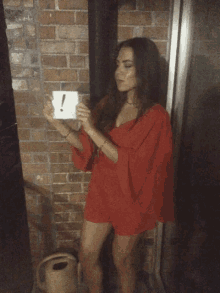 a woman in a red dress holds up a sign with an exclamation point