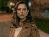 a woman wearing a brown trench coat and hoop earrings