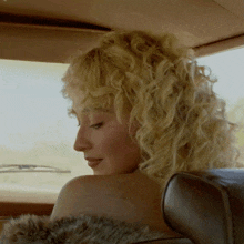 a blonde woman with curly hair is sitting in a car