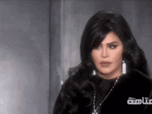 a woman with long black hair is wearing a black jacket and a necklace
