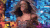 a woman in a dress is dancing in front of a colorful background