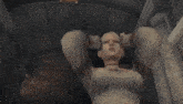a woman in a white dress is standing in front of a fireplace with her hands up .