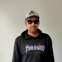 a man wearing a thrasher magazine hoodie and sunglasses