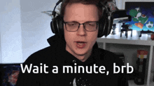 a man wearing headphones and glasses says " wait a minute brb "