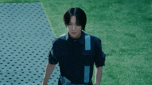 a man in a blue shirt stands in front of a grassy field