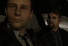 two men in suits are sitting in a car
