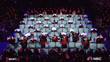 a group of people are dancing in a stadium with a nbc logo in the corner