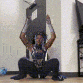 a woman with blue hair is squatting on the floor with her hands in the air