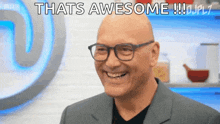 a bald man wearing glasses and a suit is smiling and saying `` that 's awesome '' .
