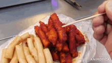 a person is holding a toothpick over a plate of food that says made in animonica