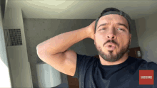 a man with a beard is wearing a hat and a black shirt with a red subscribe button