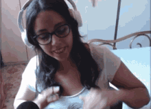 a woman wearing headphones and glasses is smiling and holding a microphone