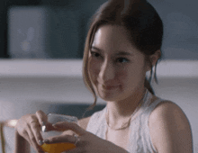 a woman is holding a glass of orange juice