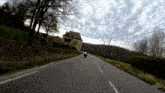 a person is riding a motorcycle down a road with a house in the background