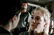 a woman with a scar on her forehead looks at a man with a beard