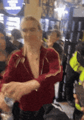 a woman in a red jacket is standing in a crowd of people