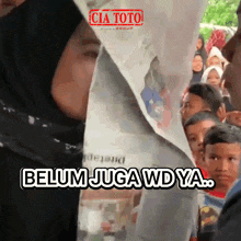 a woman in a black hijab stands in front of a crowd of people and says belum juga wd ya