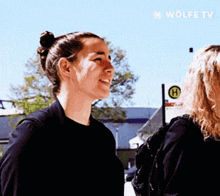 two women standing next to each other with a sign that says wolfe tv