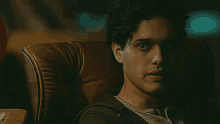 a man with curly hair is sitting in a chair and looking at the camera .
