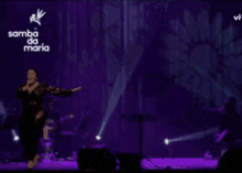 a woman singing on a stage with the words samba da maria in white letters