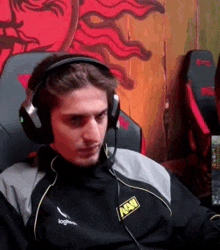 a man wearing headphones and a microphone is sitting in a chair in front of a computer .