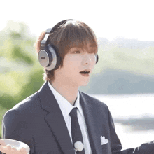 a man in a suit and tie is wearing headphones and talking .