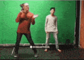 a man and a boy are dancing in front of a green screen that says dhimaakthode