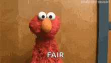 elmo from sesame street is standing in front of a wooden wall and says `` fair '' .