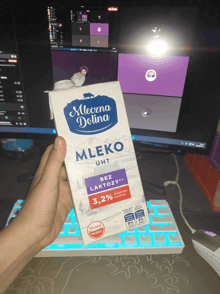 a person holding a carton of mleczna dolina mleko uht
