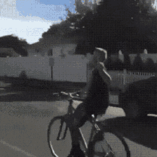 a person is riding a bike down a street with a white fence in the background .