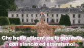 a woman in a fancy dress sits in a garden in front of a large white building