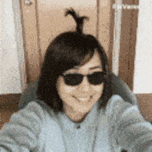 a woman wearing sunglasses and a ponytail is taking a selfie with her phone .