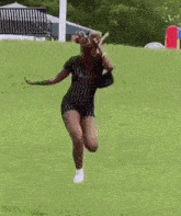 a woman is running down a grassy hill .