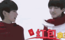 a couple of young men are standing next to each other and talking to each other .