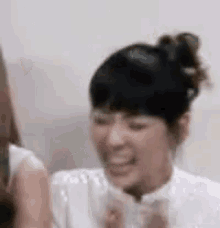 a woman in a white shirt is smiling and laughing while standing next to another woman .