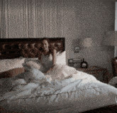 a woman is sitting on a bed with a picture of a dog on the wall