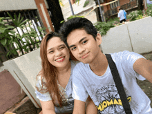 a man and a woman are posing for a selfie and the man is wearing a shirt that says momar